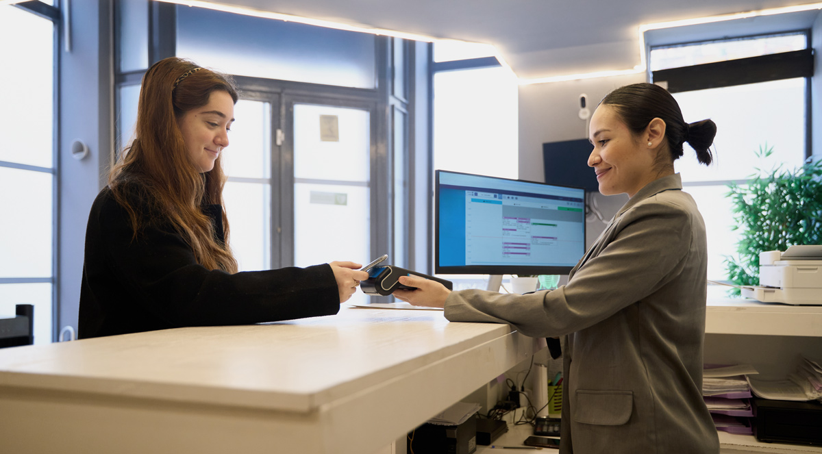 woman at dentists reception paying, dentists staying competitive with content creation services