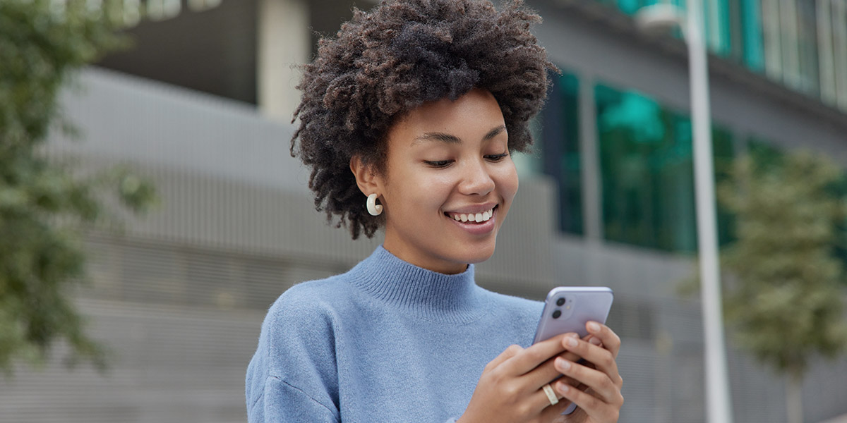 Woman smiling at mobile phone at mobile friendly dental website