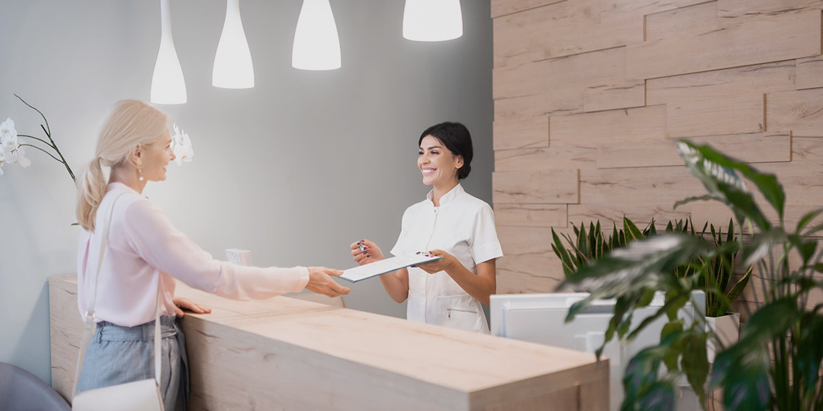 Woman at dental reception talking and why NAP consistency for dentists matters