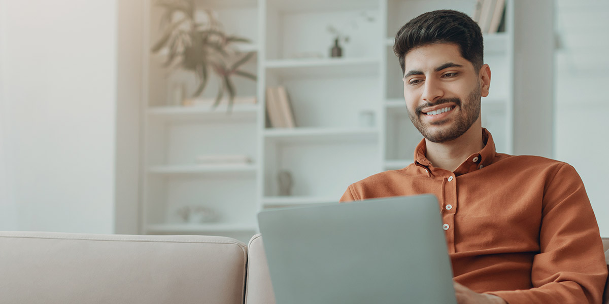 man looking at laptop smiling at dental treatment page SEO