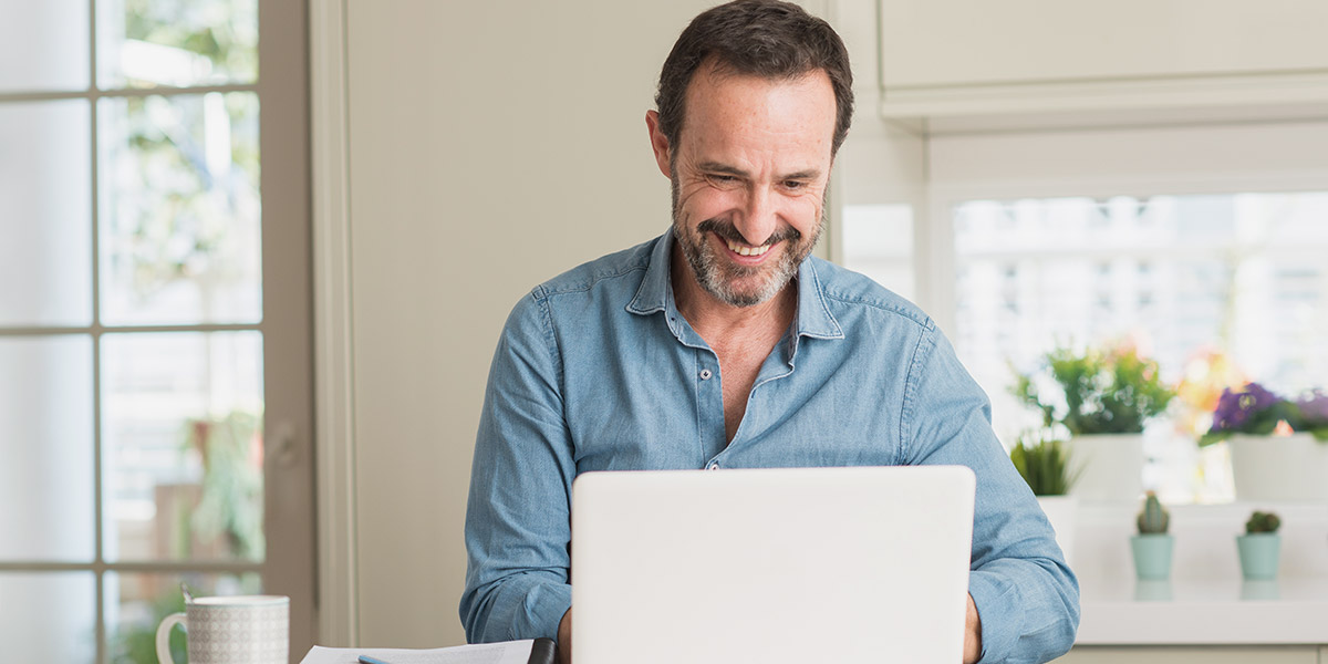 Man looking at laptop smiling at custom dental websites