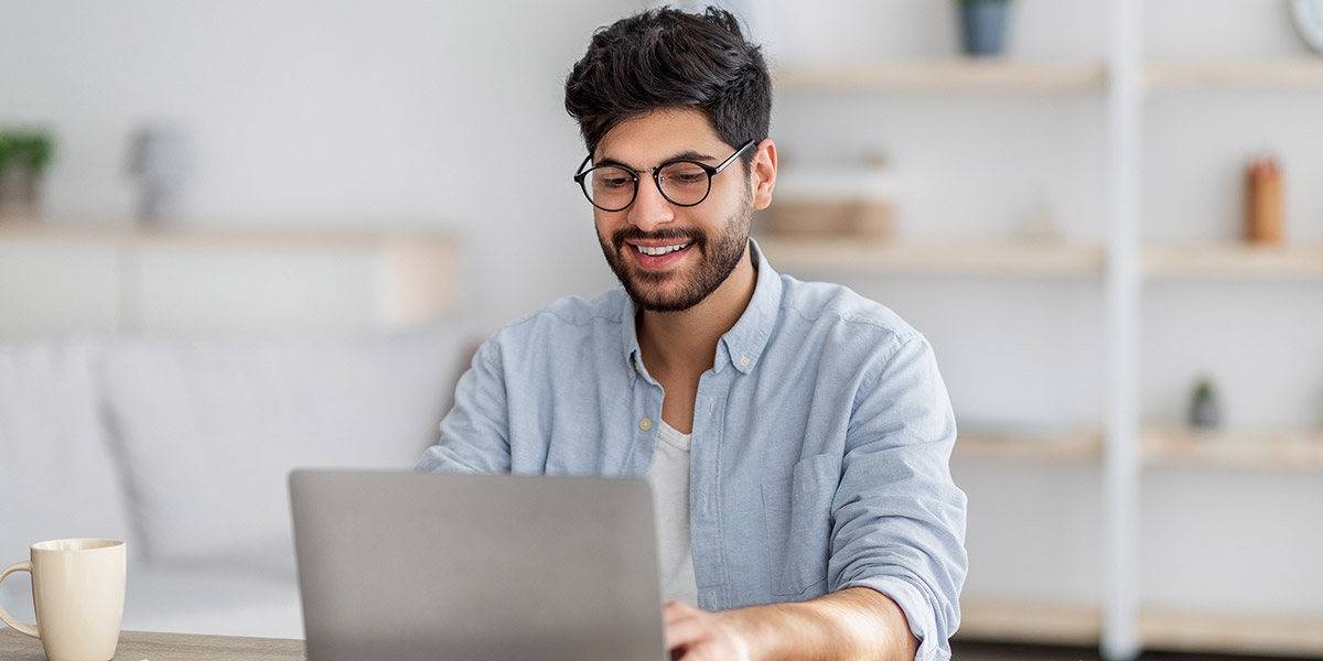 Man smiling at laptop for topical authority for dentists